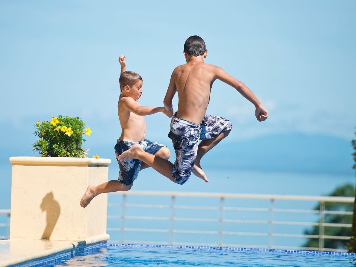 Dos niños saltando a la piscina en Los Altos Resort