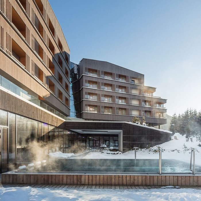 Exterior view of Falkensteiner Hotel Schladming, featuring outdoor pool area in winter