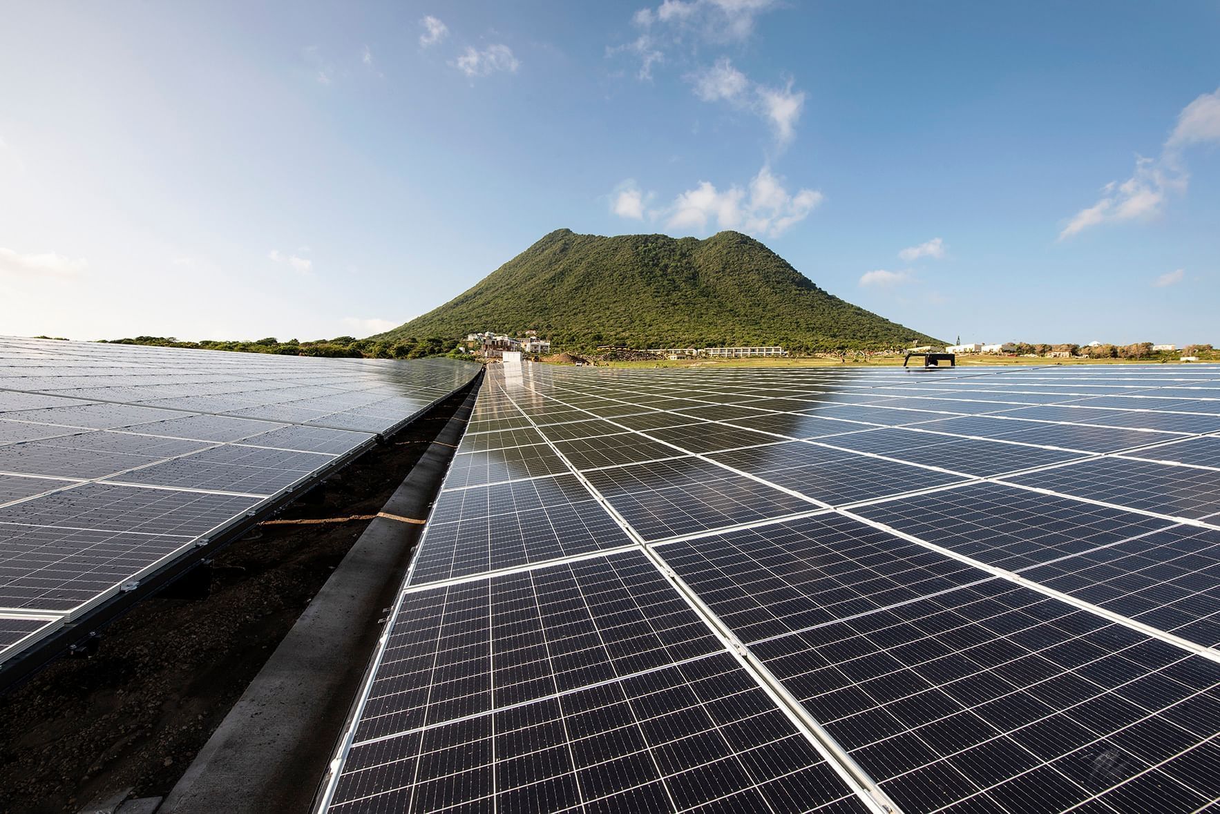 Large solar panel array with green mountain under blue sky in background near Golden Rock Resort