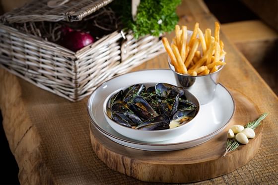 Fries and Mussles served on a decorative wooden plate, Edwardian Hotels Group
