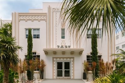 Kenmore Village Hotel South Beach, featuring decorative beige trim and lush tropical landscaping, an Art Deco hotels Miami FL