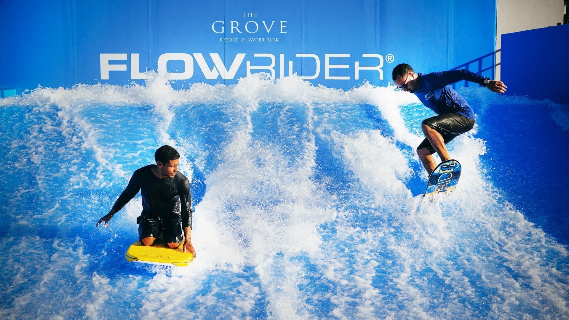 Flow riders skillfully ride a wave on surfboards at Surfari Water Park Resort