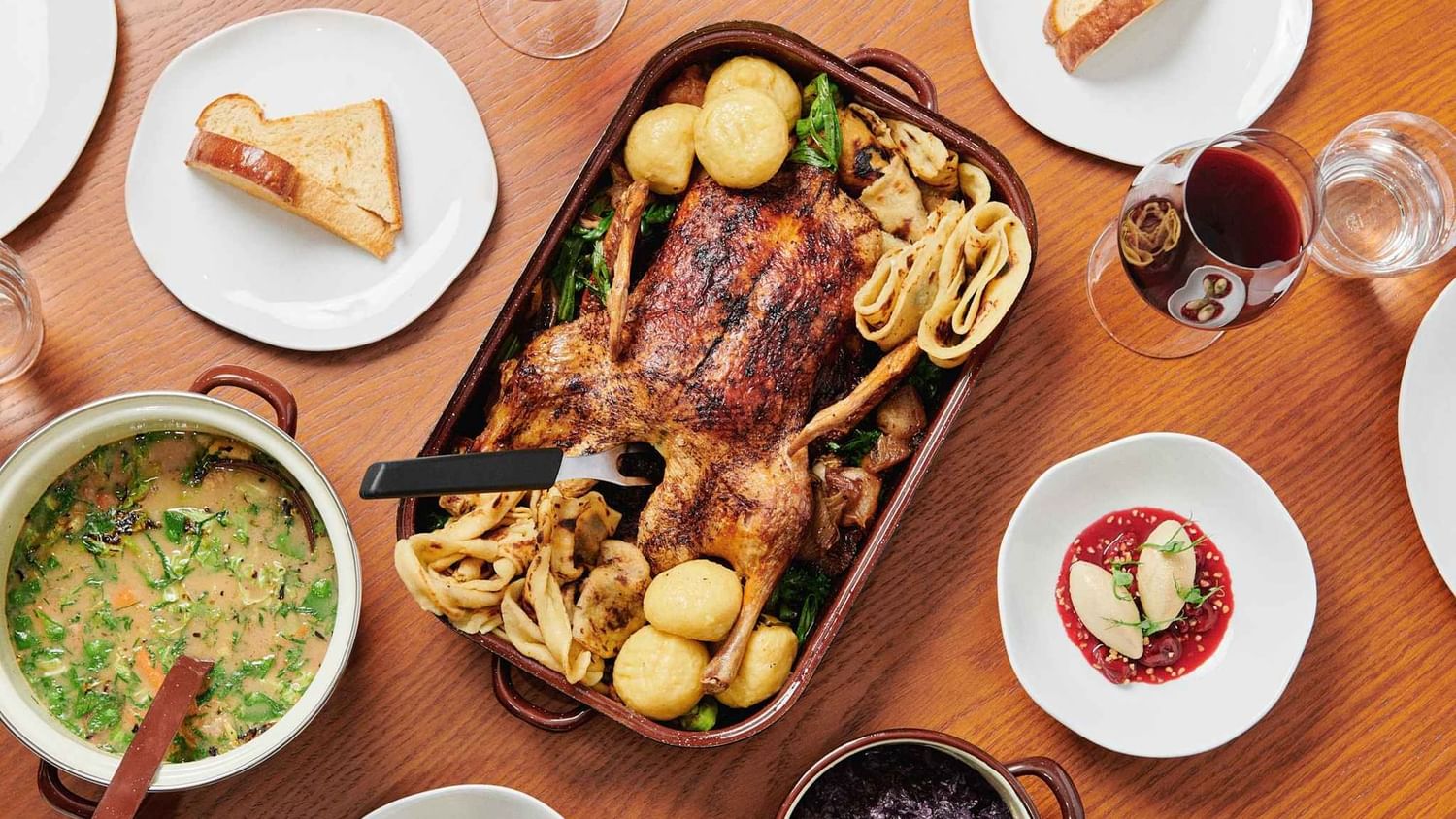Roasted chicken with soup, bread, salad, and red wine served on a table at Almanac X Alcron Prague