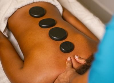 Hot stone massage therapy with four smooth stones placed along the spine at Playa Blanca Beach Resort