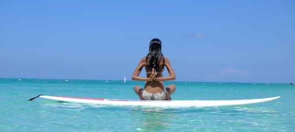A girl relaxing on a surfboard near The Somerset On Grace Bay