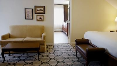 Lodge mini Suite at The Stanley Hotel featuring a bed, couch with a table and portraits hanging on the wall