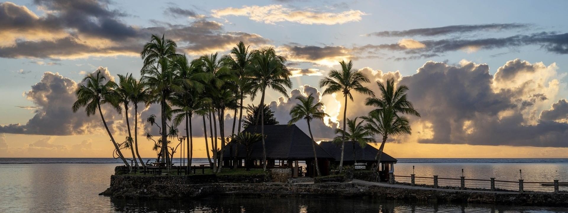Wicked Walu by a quiet sea under a golden sunset near tropical palms at Warwick Fiji Resort and Spa