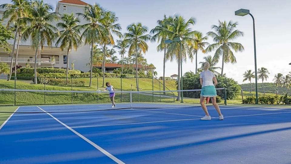 Dos mujeres jugando tenis en la cancha al aire libre de Las Casitas Village.
