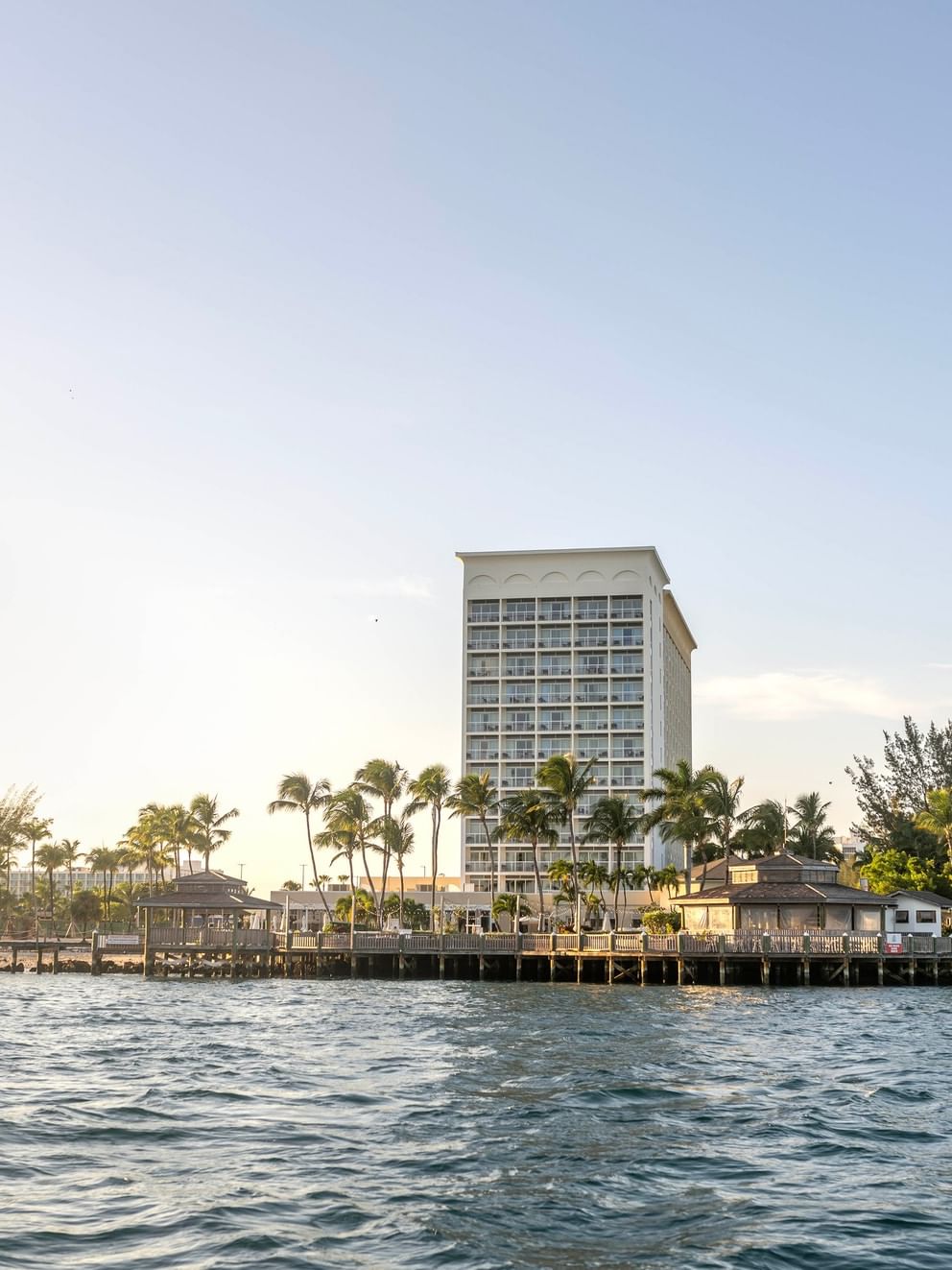 Waterfront view of Warwick Paradise Island hotel with palm trees and a clear sky.