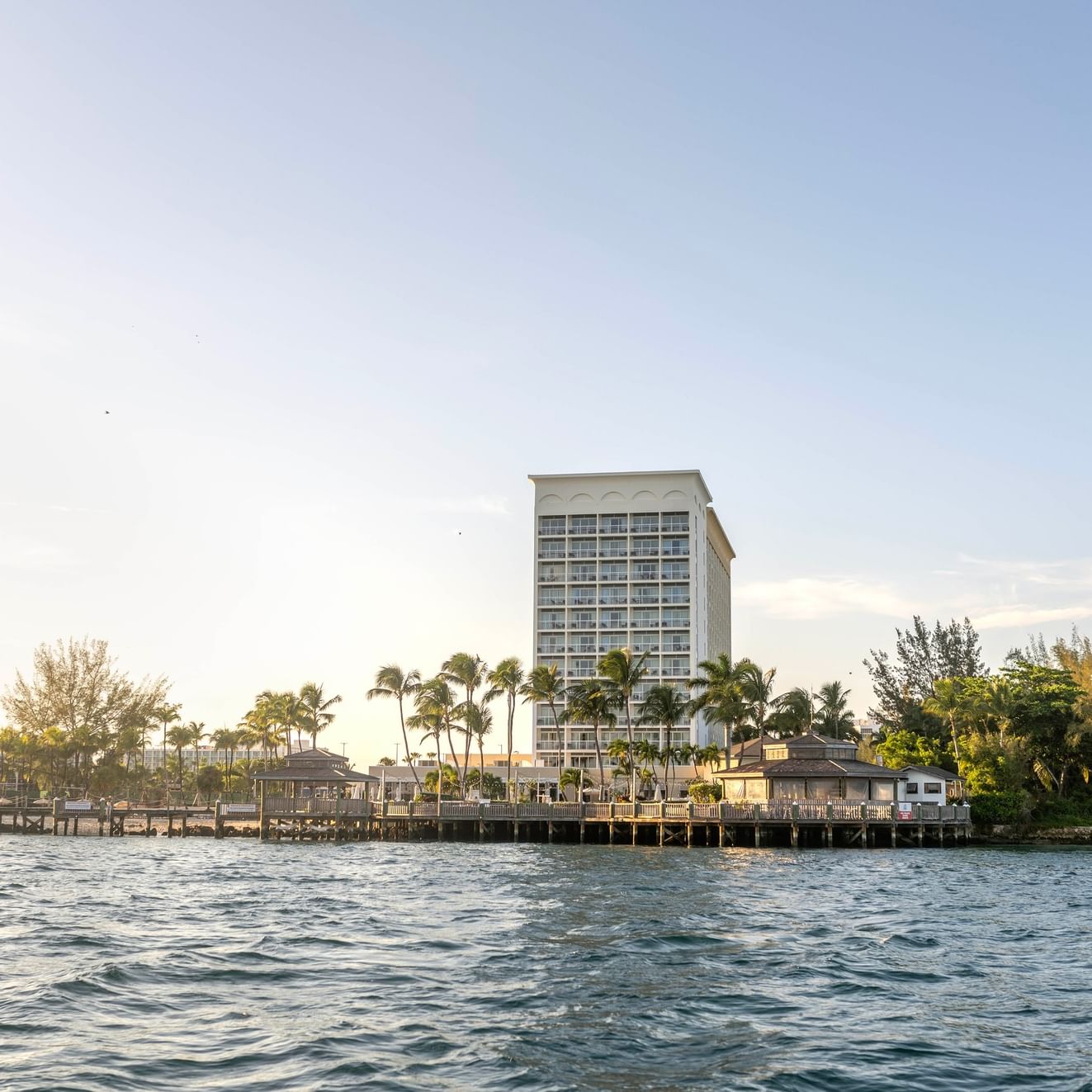 Vue sur le front de mer de l'hôtel Warwick Paradise Island, avec des palmiers et un ciel dégagé.
