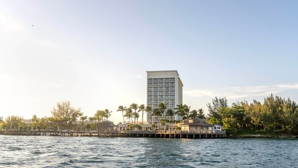 Waterfront view of Warwick Paradise Island hotel with palm trees and a clear sky.