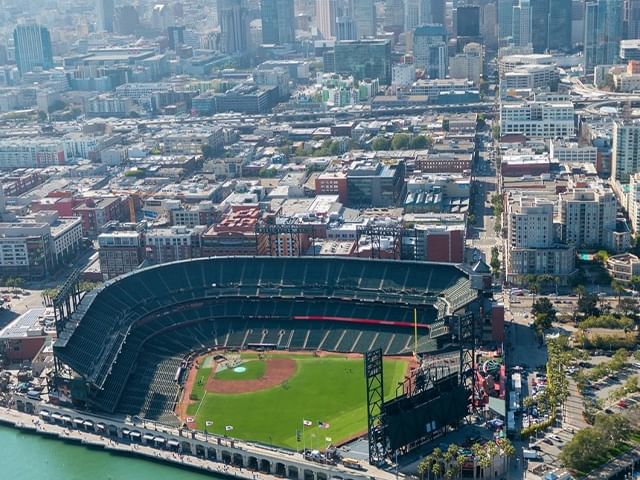 Panoramic aerial view of a city with a baseball stadium by a harbor.
