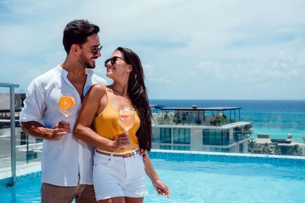 A couple having drinks on the pool deck at The Reef Resorts