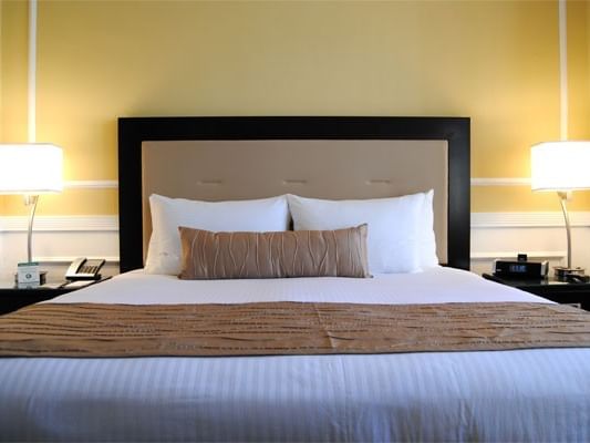 A luxurious hotel room with a neatly made bed, two nightstands, and bedside lamps at Pickwick San Francisco.