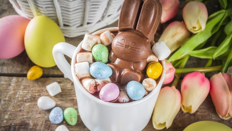 Chocolate bunny in a cup of hot cocoa with marshmallows and candies for Easter School Holidays Activities.