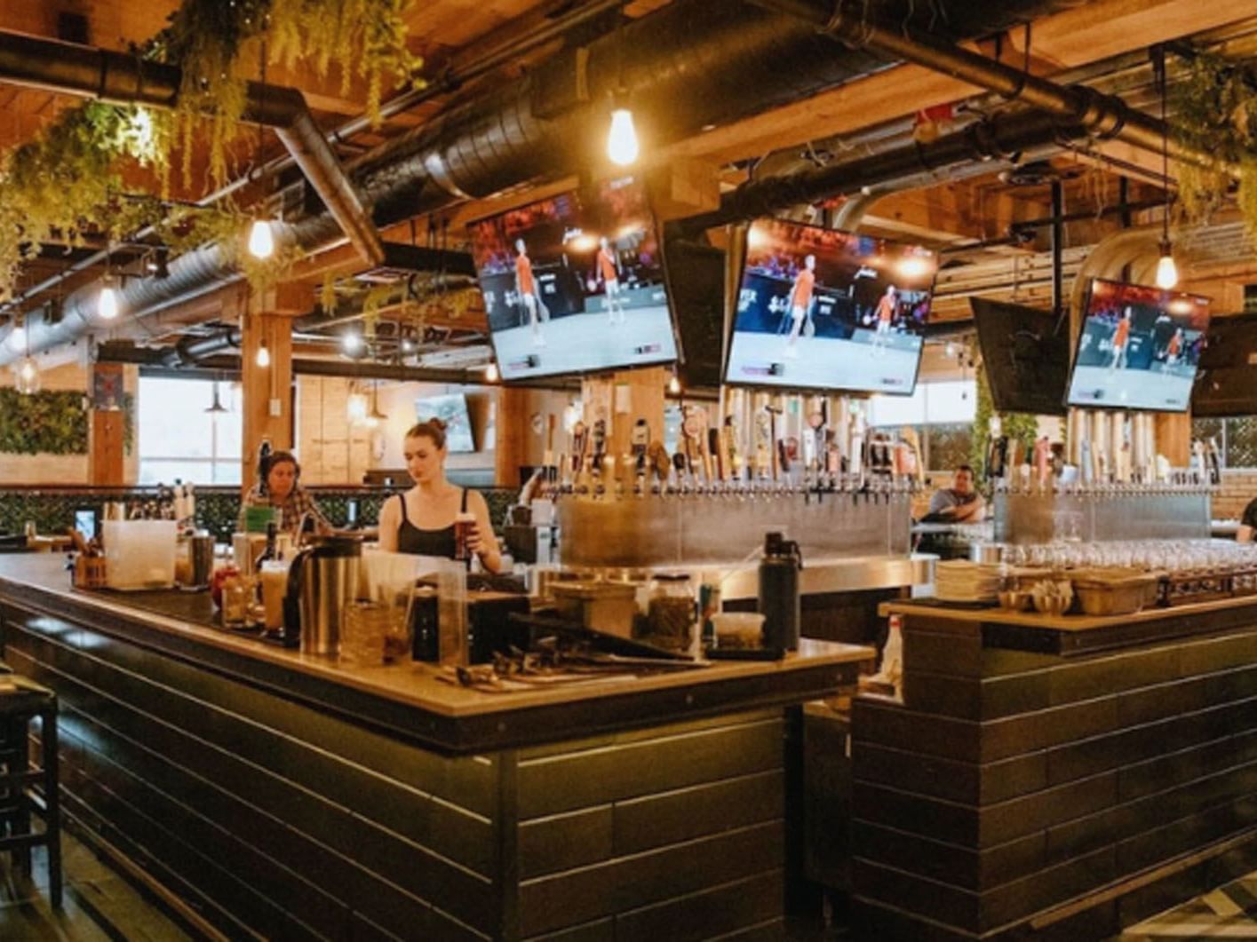 The Craft Brasserie & Grille with taps, hanging lights, and mounted TVs near Hotel X, a hotel in Toronto