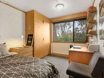 A tidy dorm room with a bed, desk, chair, and window at La Trobe University - Chisholm College.