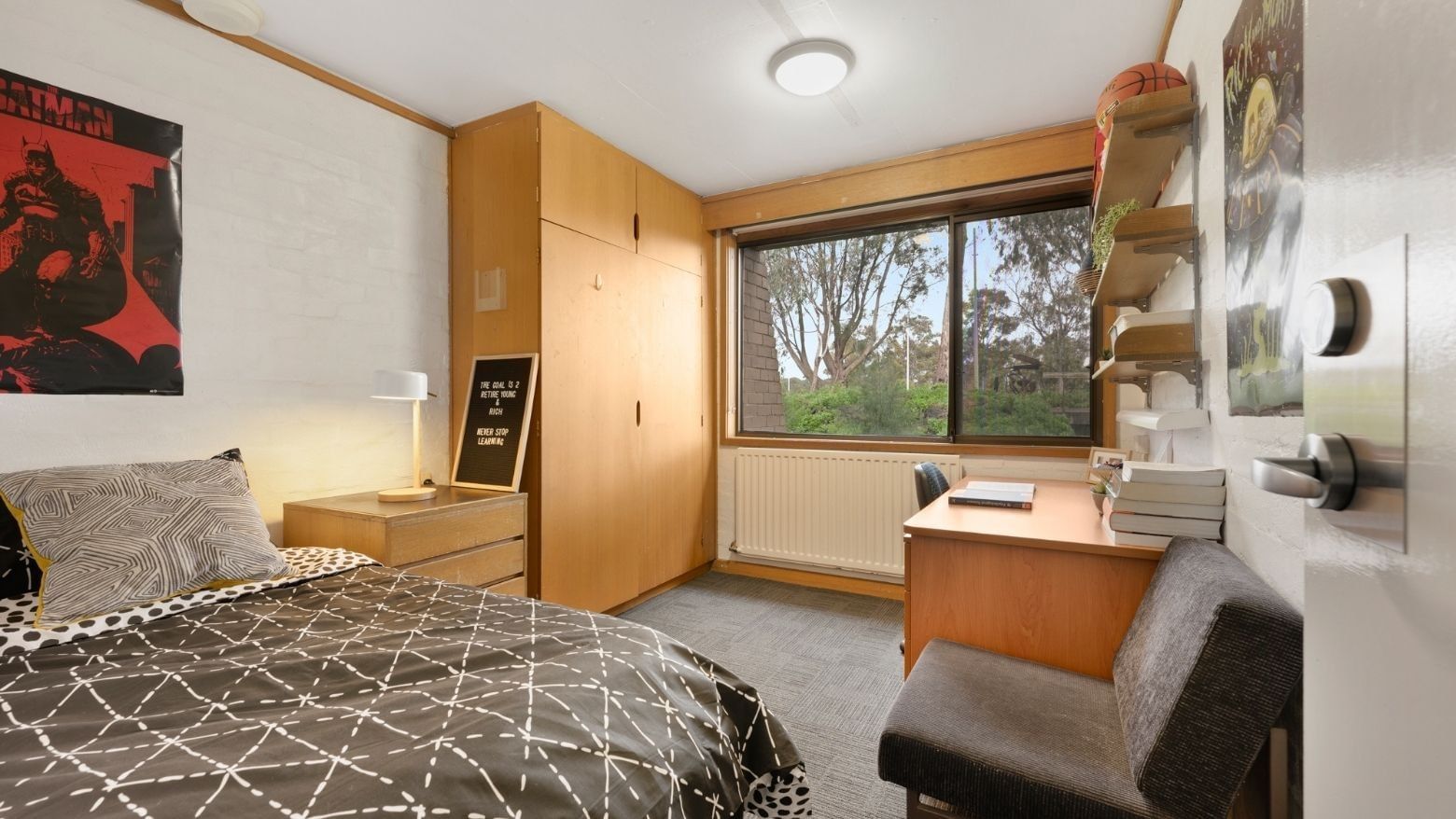 A tidy dorm room with a bed, desk, chair, and window at La Trobe University - Chisholm College.