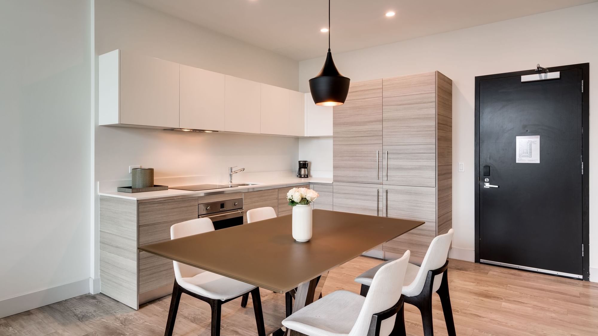 A modern kitchen and dining area with a brown table and white chairs.