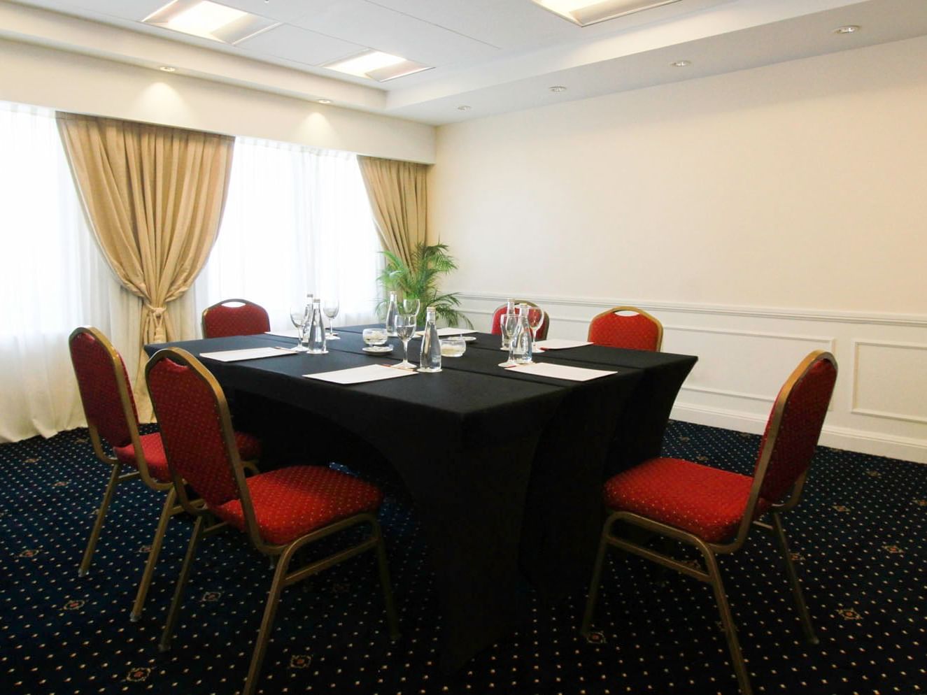 Alcala meeting room arranged with tables and red chairs at Hotel Emperador Buenos Aires
