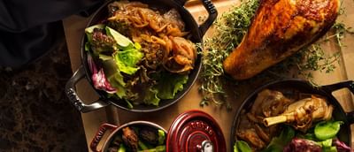 Wooden platter with a roasted turkey leg, fresh salad, and gourmet sides in ​​Square One at Park Hyatt Saigon