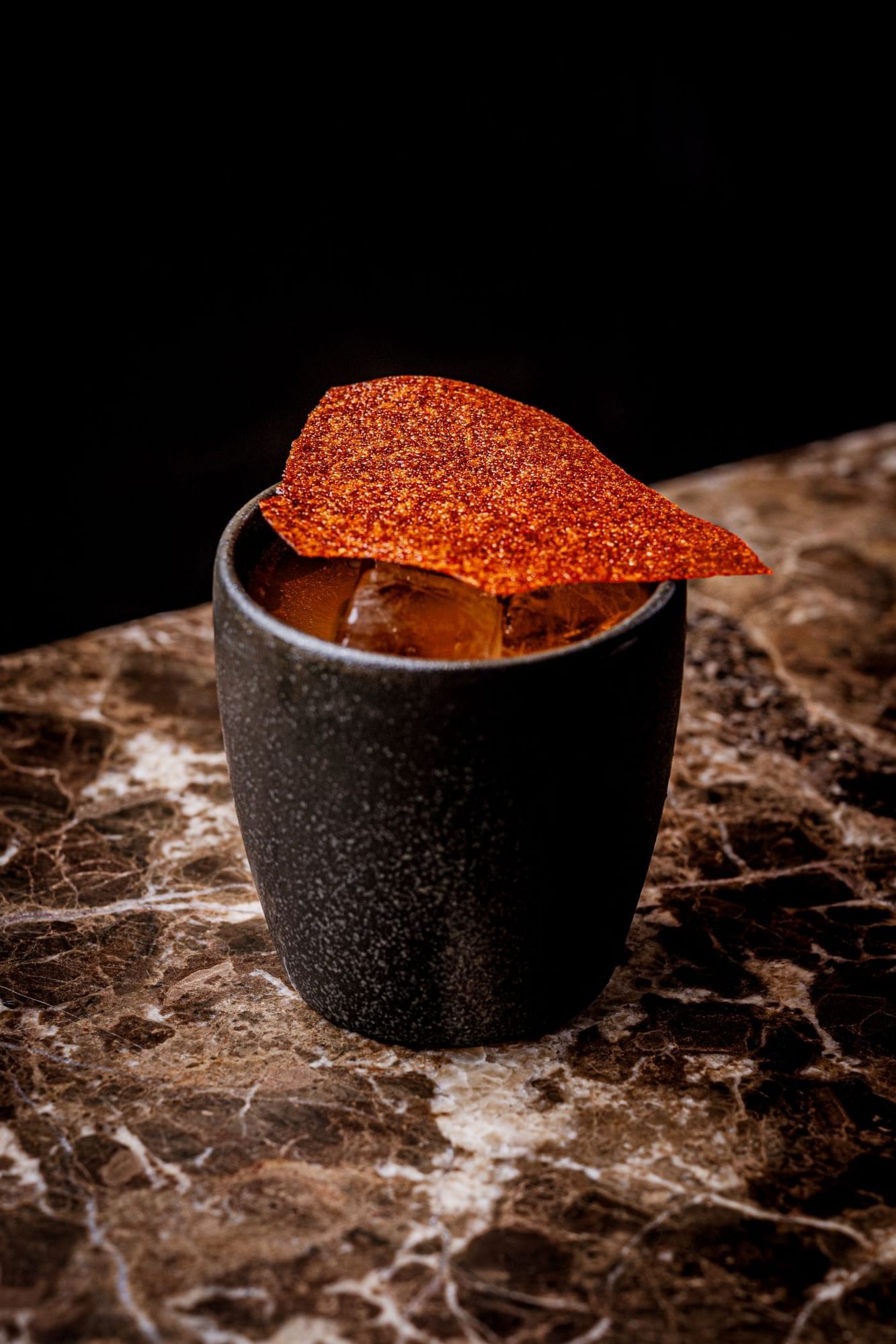A black cup with a taco garnish on top of a cocktail inspired by Mexico day of the dead at The May Fair Bar