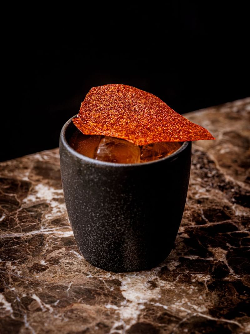 A black cup with a taco garnish on top of a cocktail inspired by Mexico day of the dead at The May Fair Bar