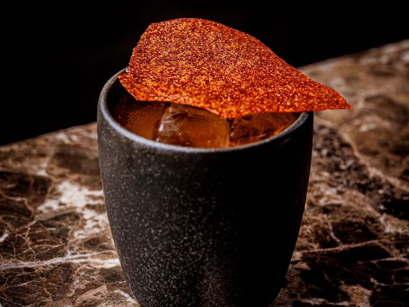 A black cup with a taco garnish on top of a cocktail inspired by Mexico day of the dead at The May Fair Bar