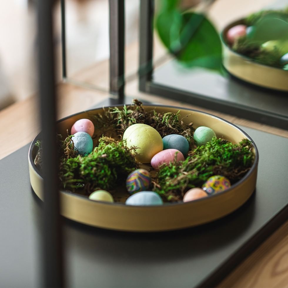 Uova di Pasqua colorate in un cestino di muschio e rami su un tavolo