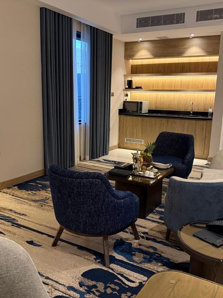 TV lounge with couches and a coffee table beside the kitchenette in One Bedroom Suite at Warwick Jeddah Hotel & Spa