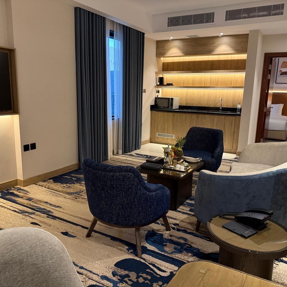 TV lounge with couches and a coffee table beside the kitchenette in One Bedroom Suite at Warwick Jeddah Hotel & Spa
