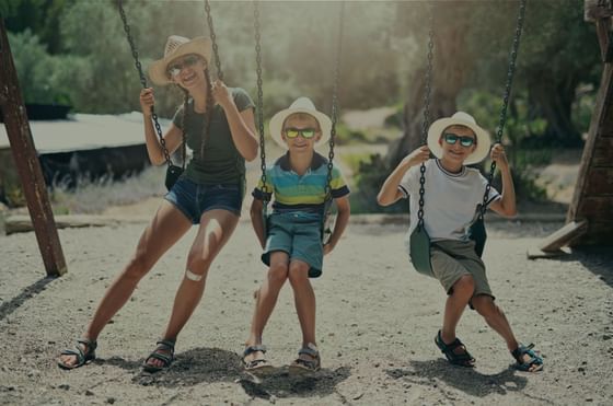 Lady & kids on swings outdoors, The Lodge at Schroon Lake