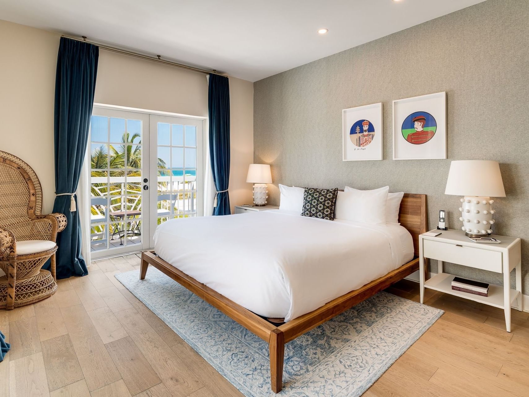 Nightstands and wicker chair by the bed in Junior King Oceanfront Suite with Balcony at The Savoy Hotel & Beach Club