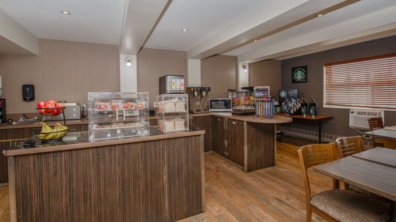 Breakfast room with wooden counters, fruits, pastries, and coffee.