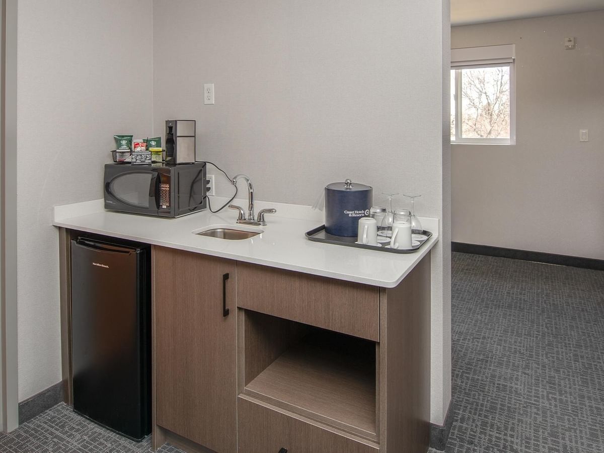 Microwave, mini-fridge, sink, and coffee maker in a hotel suite.