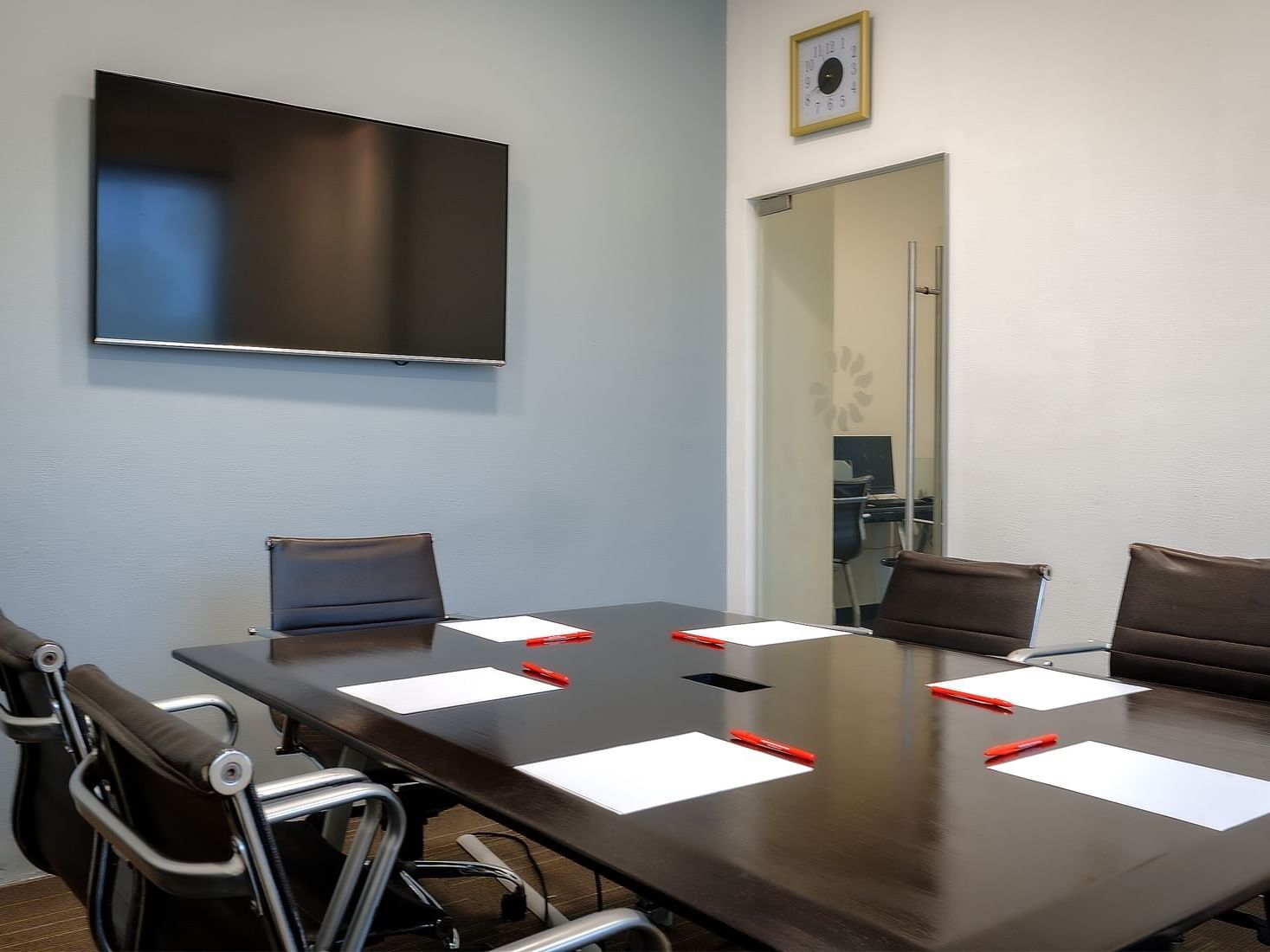 Conference room with a wooden table, black chairs, and a wall-mounted TV at Fiesta Inn Hotels