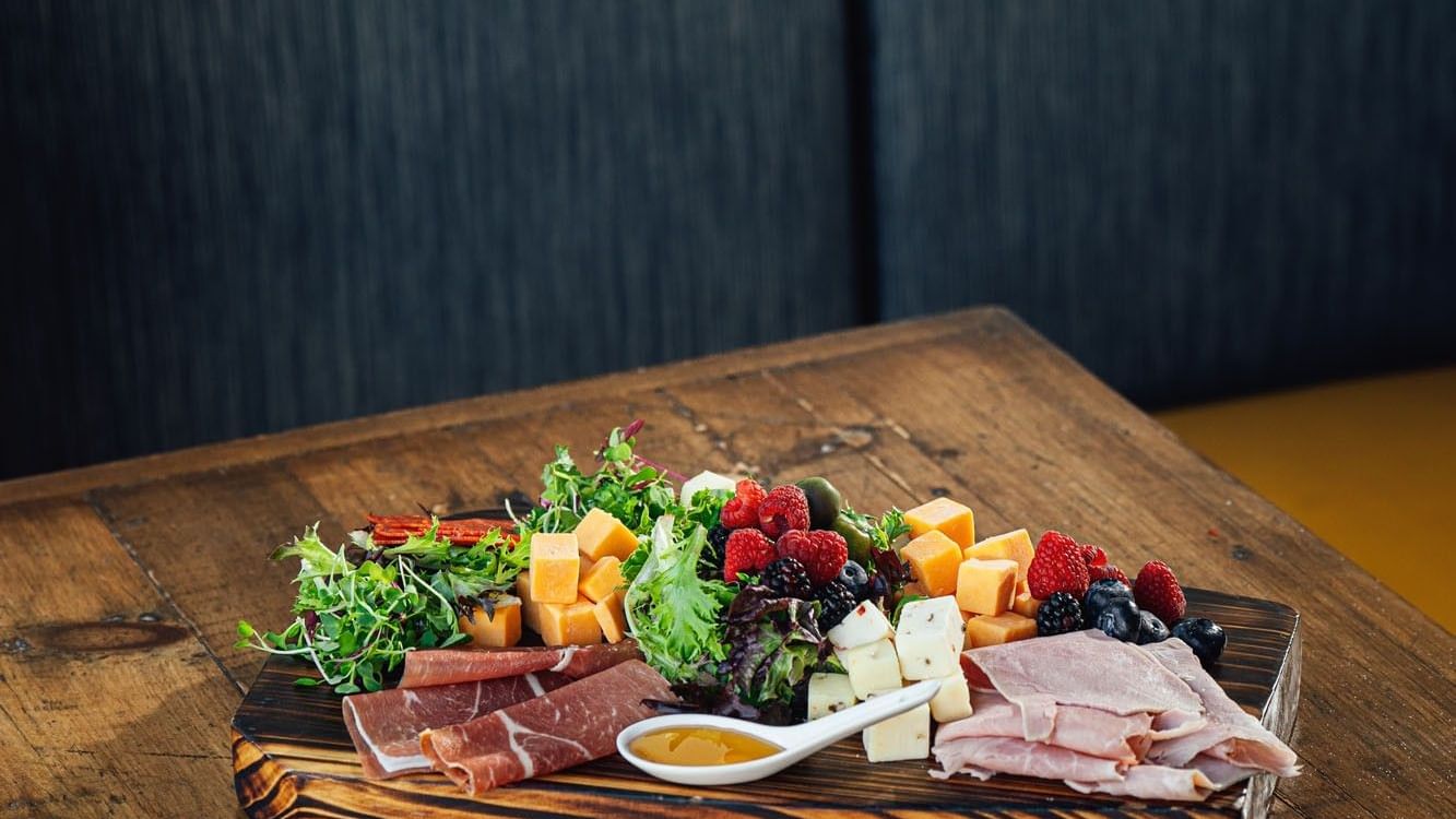 Fresh meats and cheese with berries on a wooden board in In-Room Dining at Warwick Denver