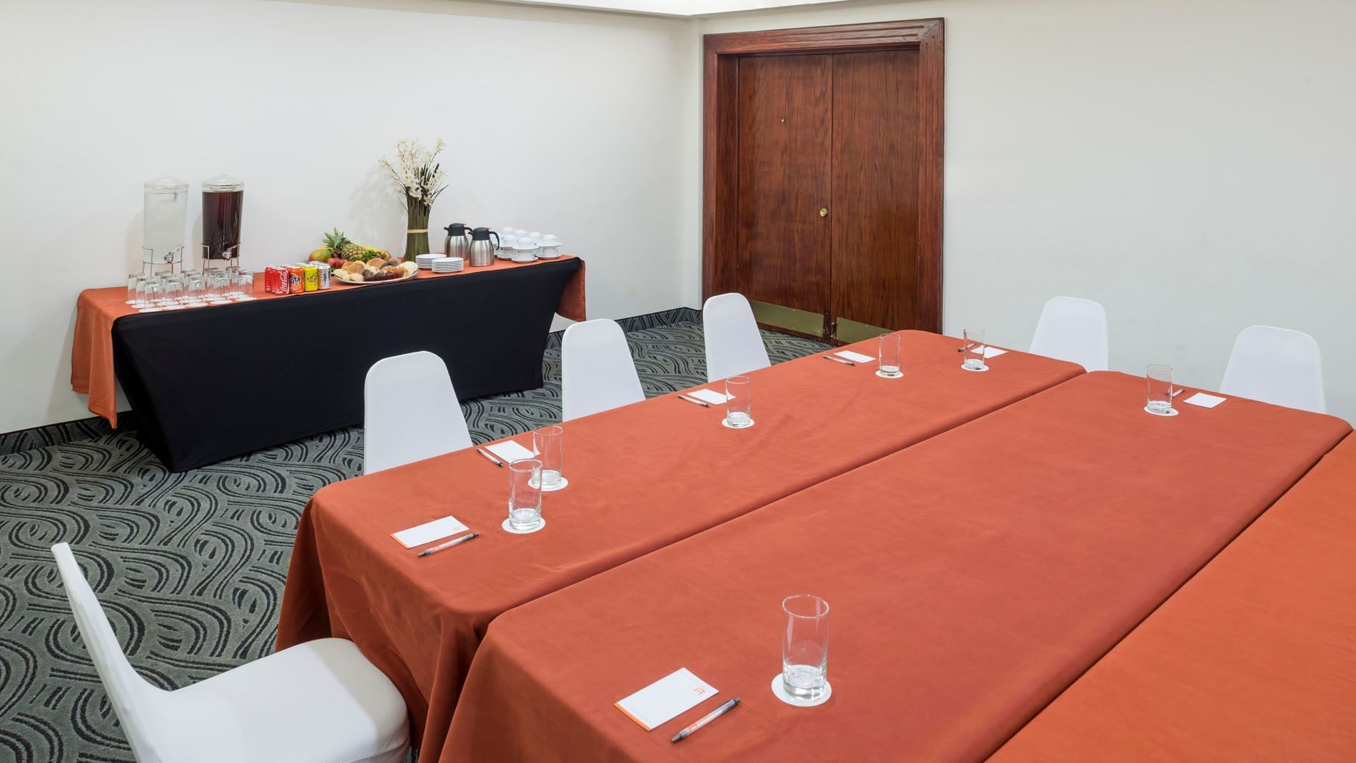 Setup table with a notepad and a water glass beside the buffet table near the door in Budapest at Real Inn Mexicali