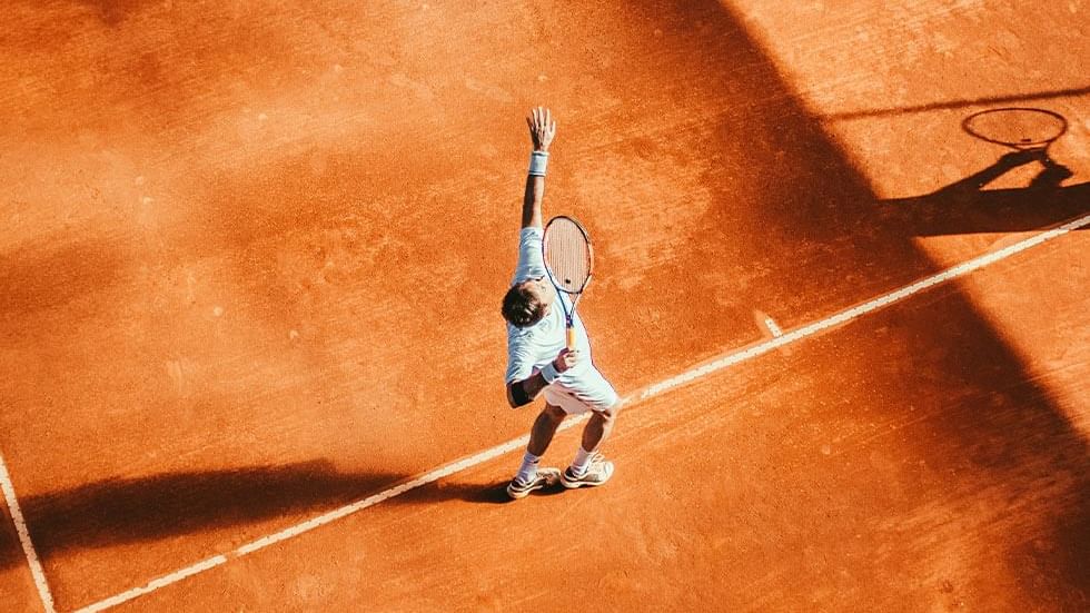 Top view of tennis player serving on a clay court near Falkensteiner Hotel Cristallo