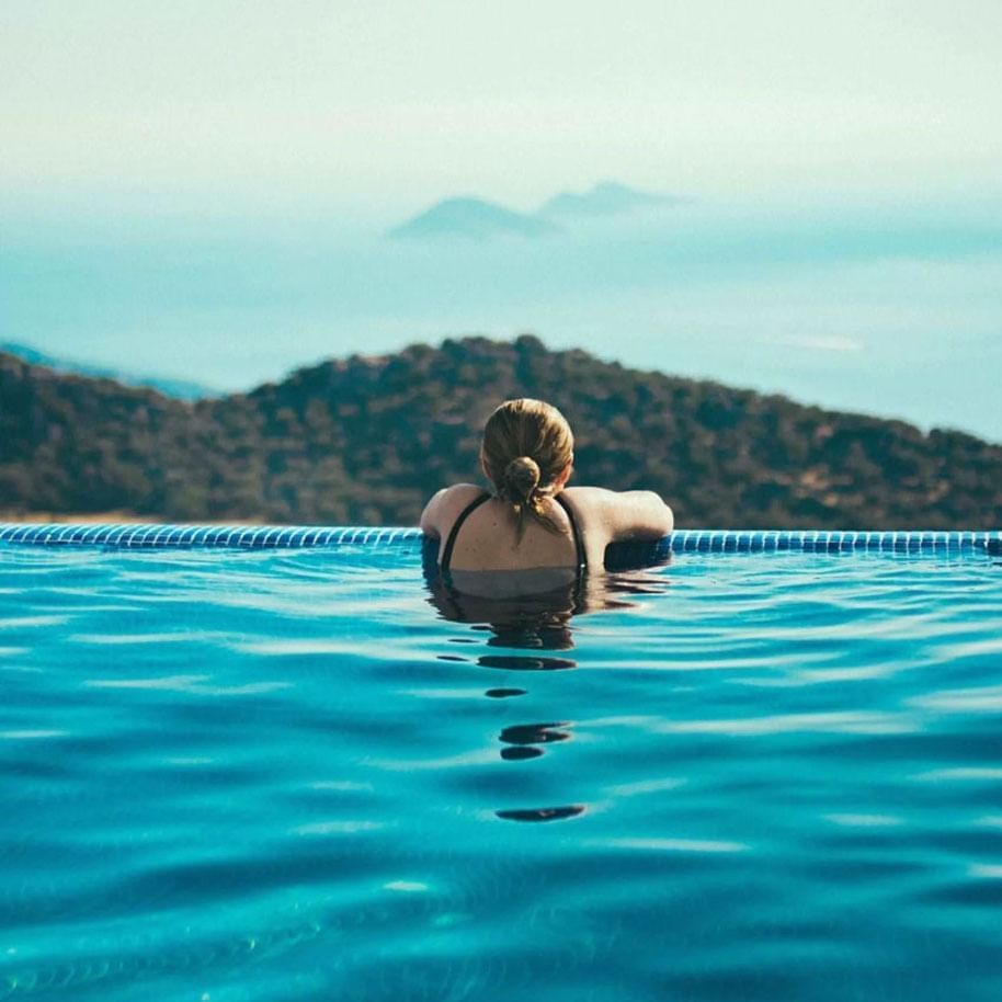 Lady relaxing in an infinity pool with a mountain backdrop at The Terraces Resort & Spa