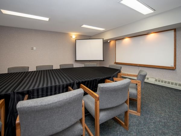 Meeting room with table, chairs, projector screen, and whiteboard.