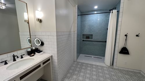 Bathroom vanity & shower area with patterned floors in King Room With Balcony at Camp Creek Inn