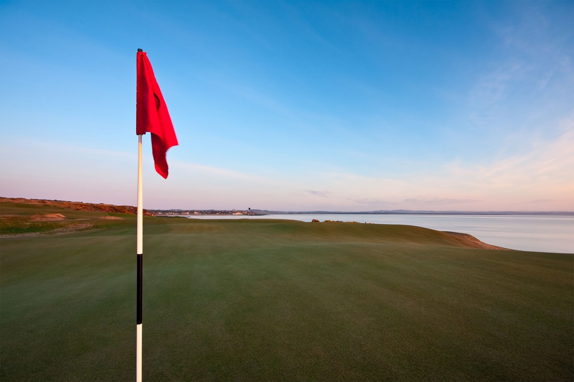 Red flag on a golf course with a coastal background at Seaton House