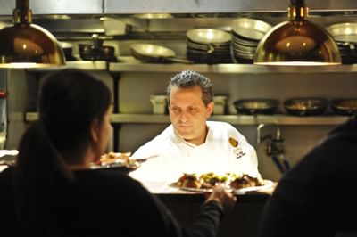 Chef preparing and passing food plates under heat lamps in the kitchen at Farmington Inn and Suites