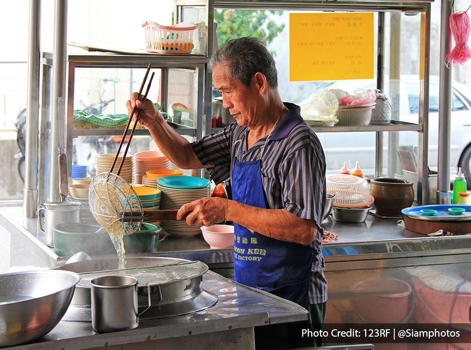 an uncle at Penang hawker food stall were preparing freshly cooked noodle for the customers