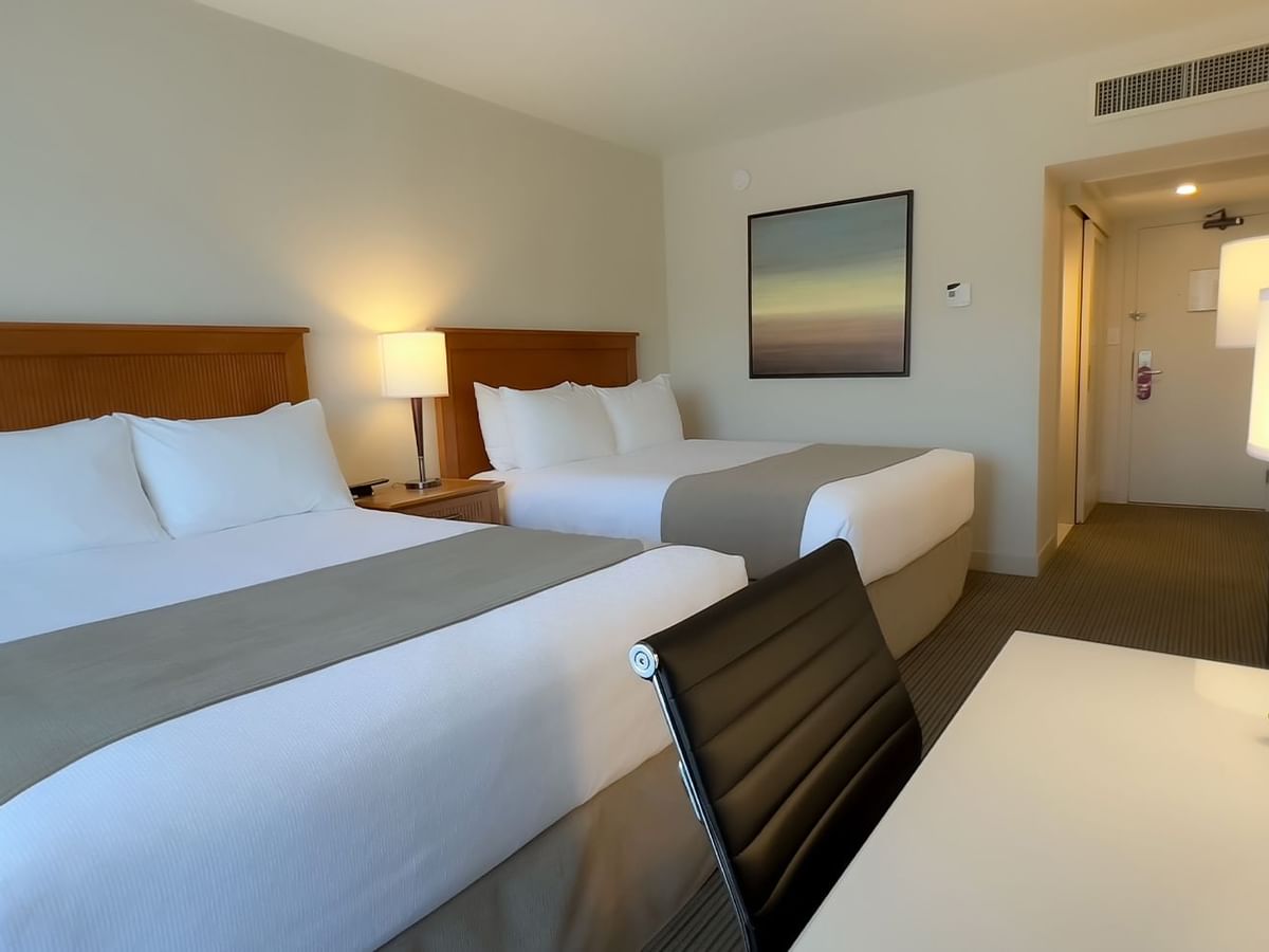 Guest room with two queen beds, desk, chair, tv, lamps