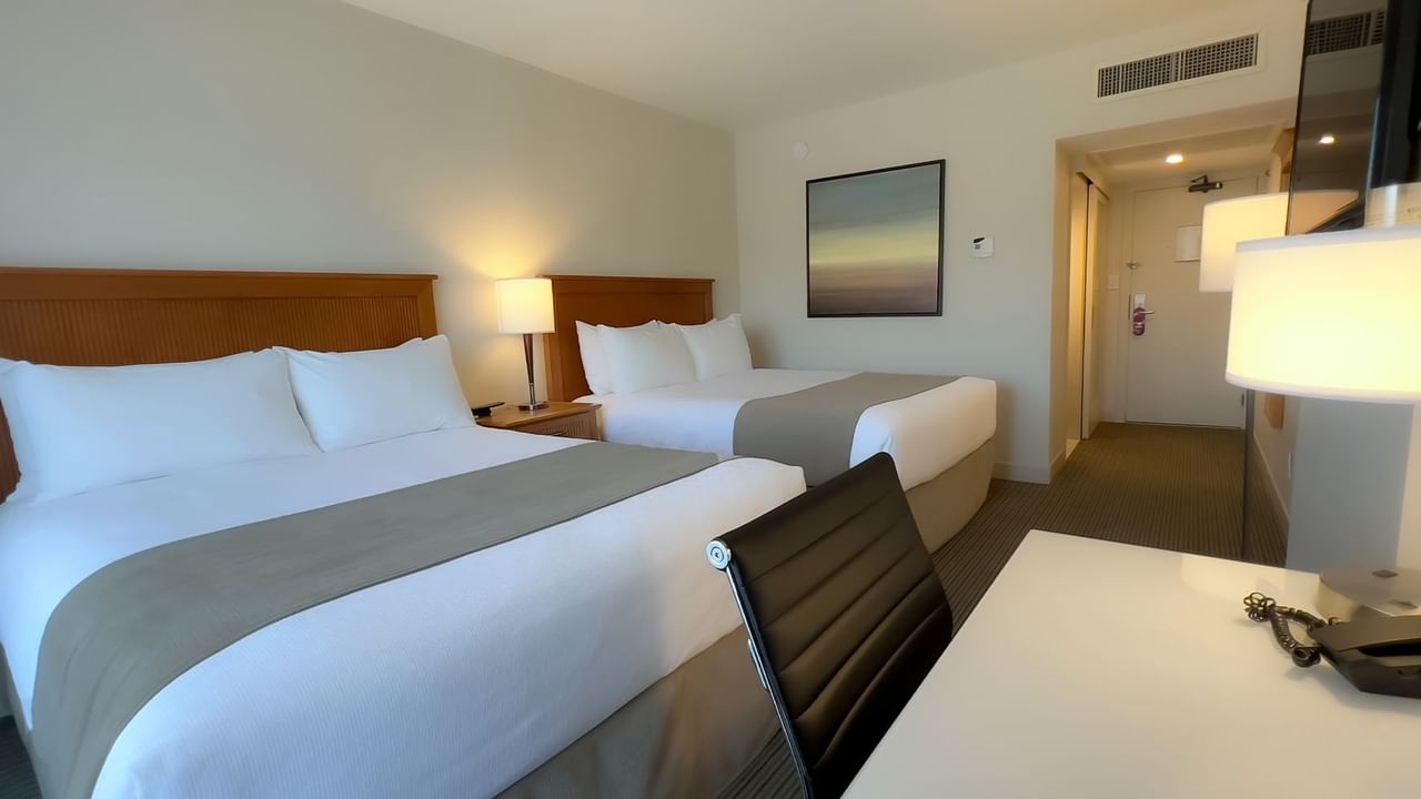 Guest room with two queen beds, desk, chair, tv, lamps