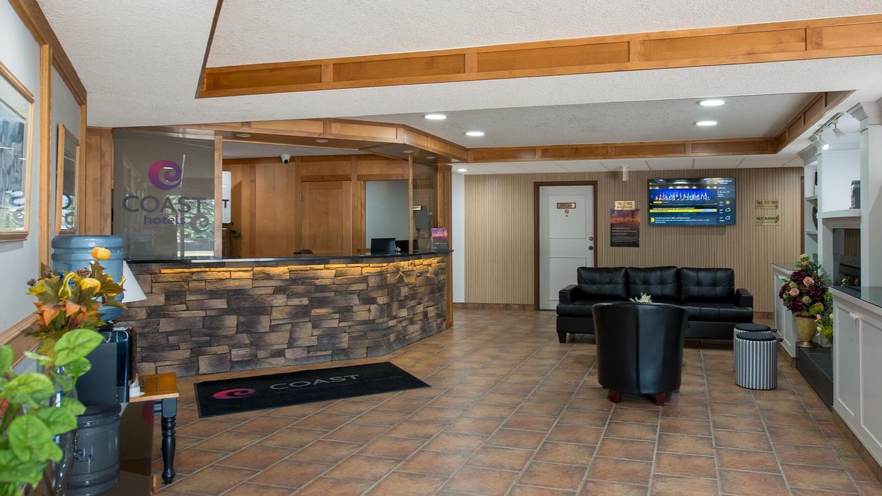 Hotel lobby with front desk, seating area and wood-panelled interior at Coast Whitecourt Hotel