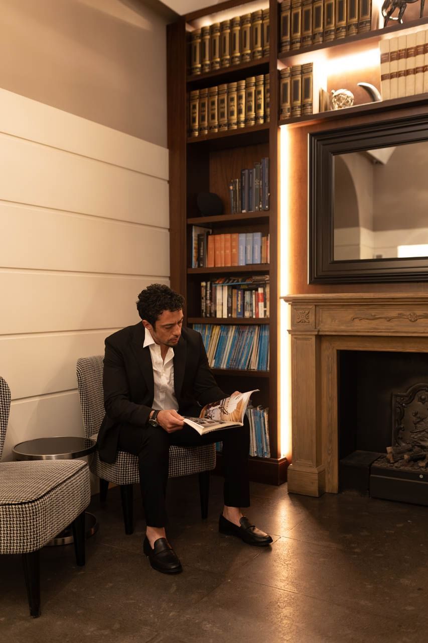 Person reads in a cozy nook at The Independent, with bookshelves and an elegant fireplace