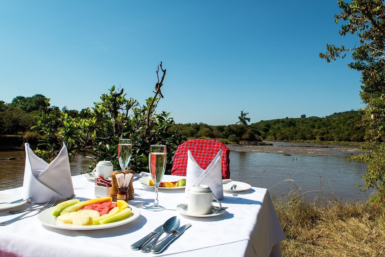 A dining table in front of a lake at Mara Serena Safari Lodge